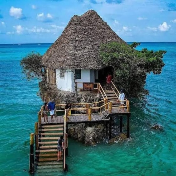 A thatched-roof house on a wooden pier extending into turquoise waters. 5