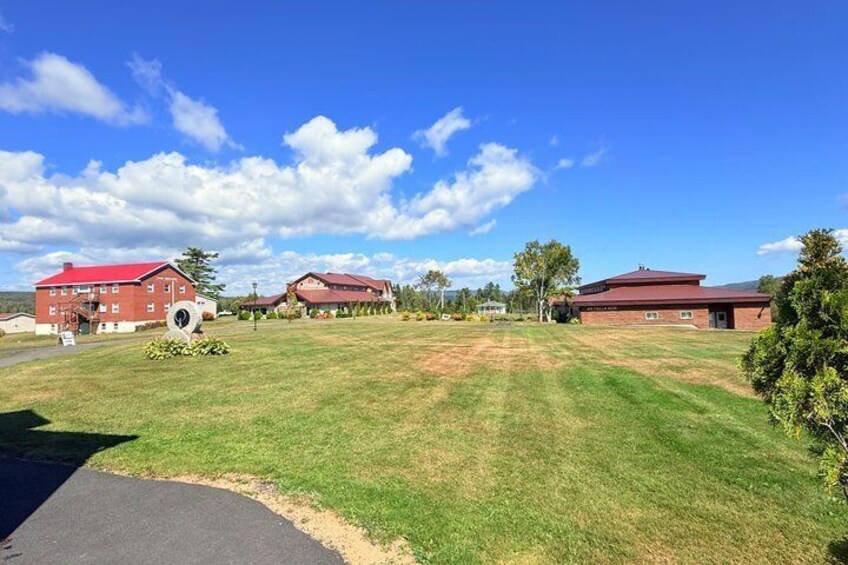 A grassy field with red-roofed buildings and a clear blue sky. 5