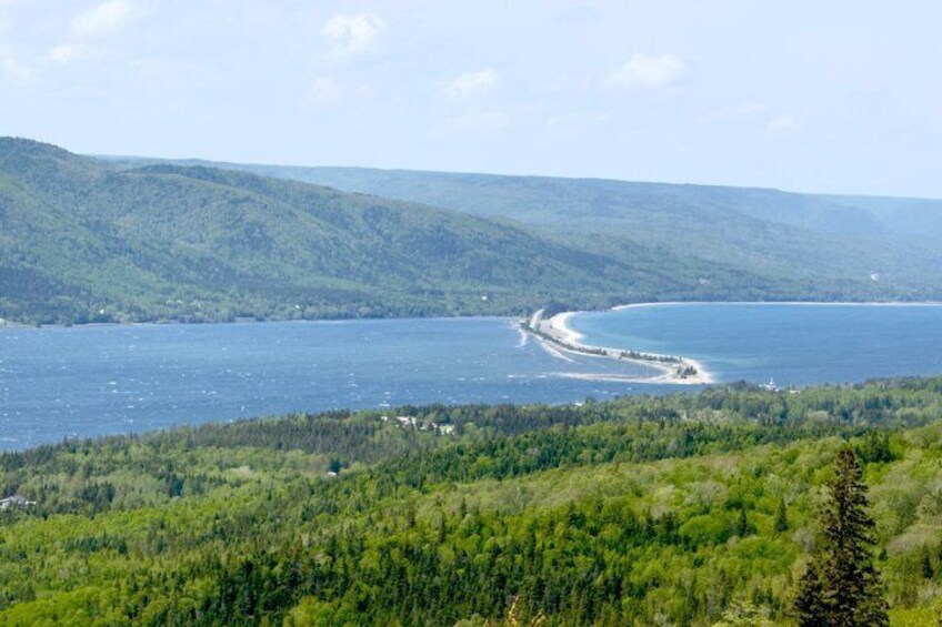 A coastal landscape with a curving shoreline, dense forest, and distant hills. 4