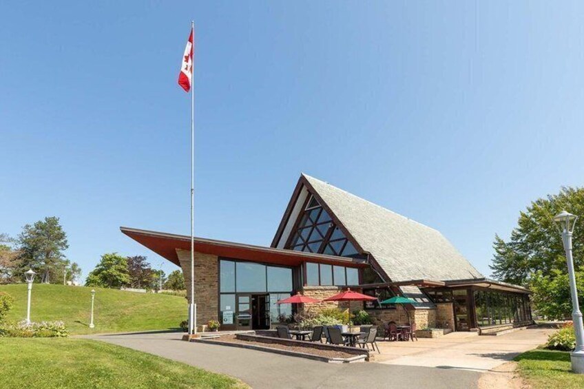 A modern building with a sloped roof, large windows, and a flagpole. 1