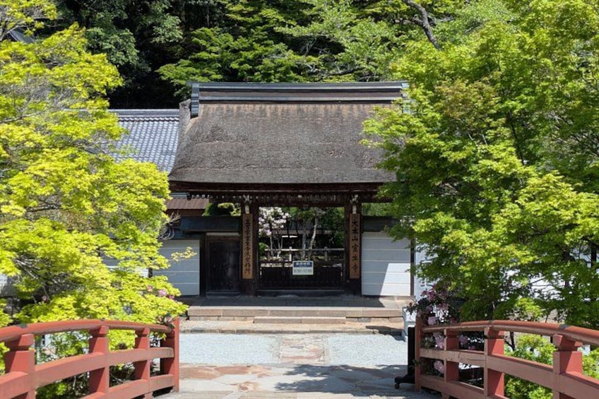 A traditional Japanese building with a tiled roof, surrounded by lush greenery and a stone pathway leading to it. 3