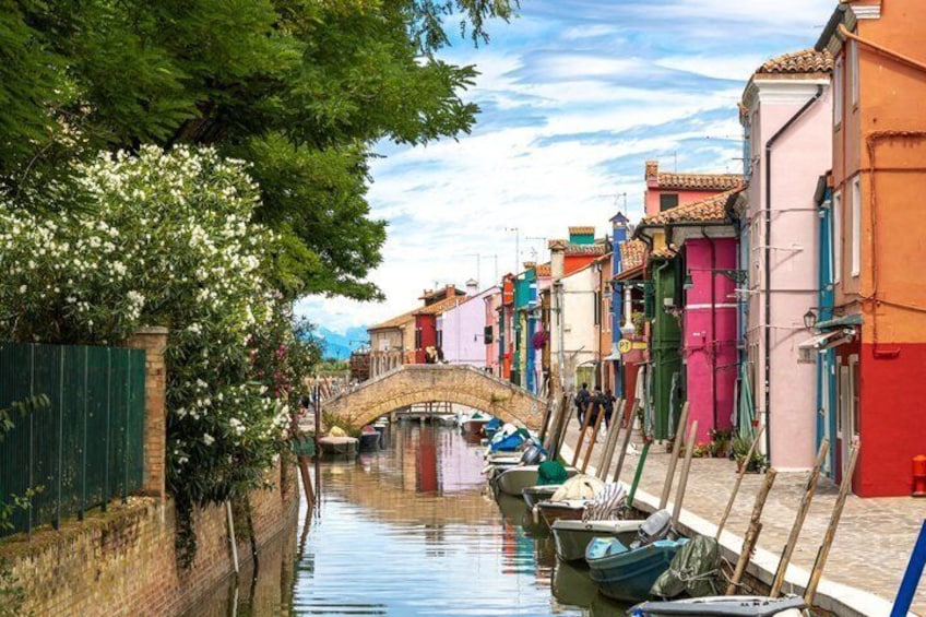 A canal with boats, a bridge, and colorful buildings. 1