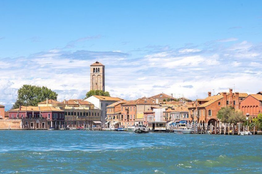 A waterfront cityscape with historic buildings, a prominent tower, and a calm sea. 2