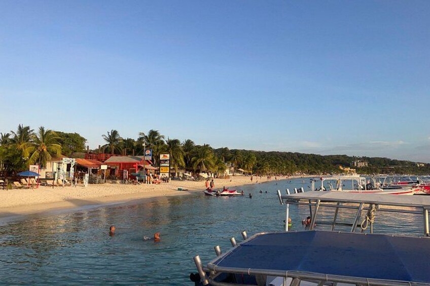 A beach with boats, palm trees, and a clear sky. 2