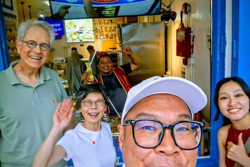 A group of people in a restaurant with a blue interior and a fire extinguisher on the wall. 1