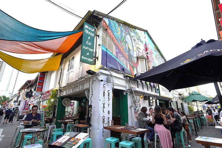 A street with outdoor seating, a colorful mural, and a sign for a restaurant. 3
