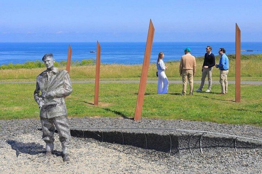 A statue, a grassy area, and a body of water. 2