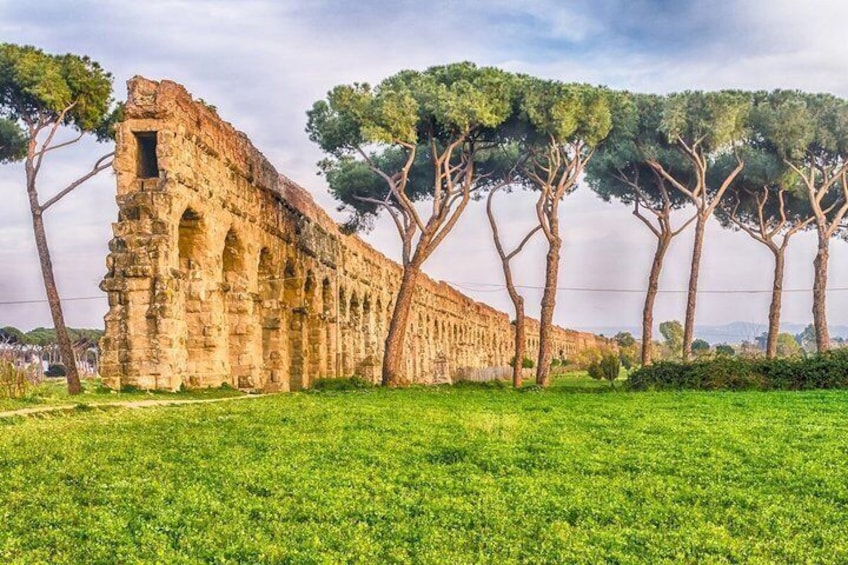 Ancient ruins with arches and trees in a grassy field. 5