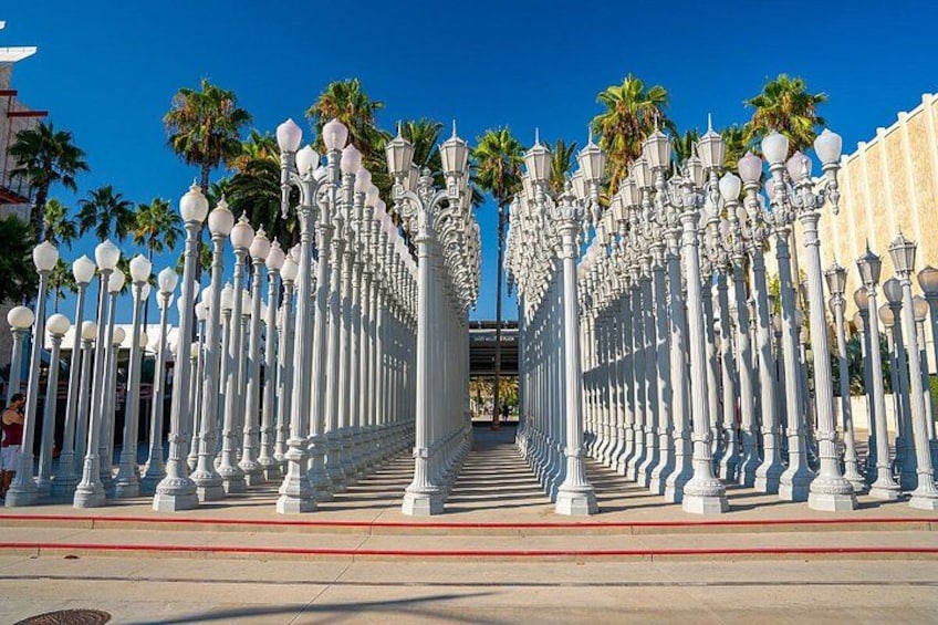 A symmetrical street with white lampposts and palm trees. 2