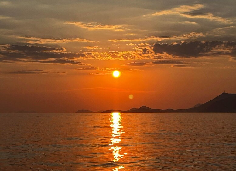 A sunset over a calm sea with a distant mountain range. 3
