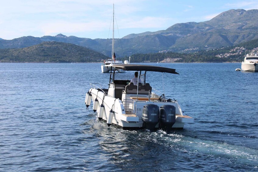 A white motorboat with a canopy on a calm lake, surrounded by hills and other boats. 4