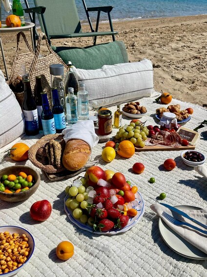 A picnic setup on a beach with food, drinks, and a view of the sea. 5