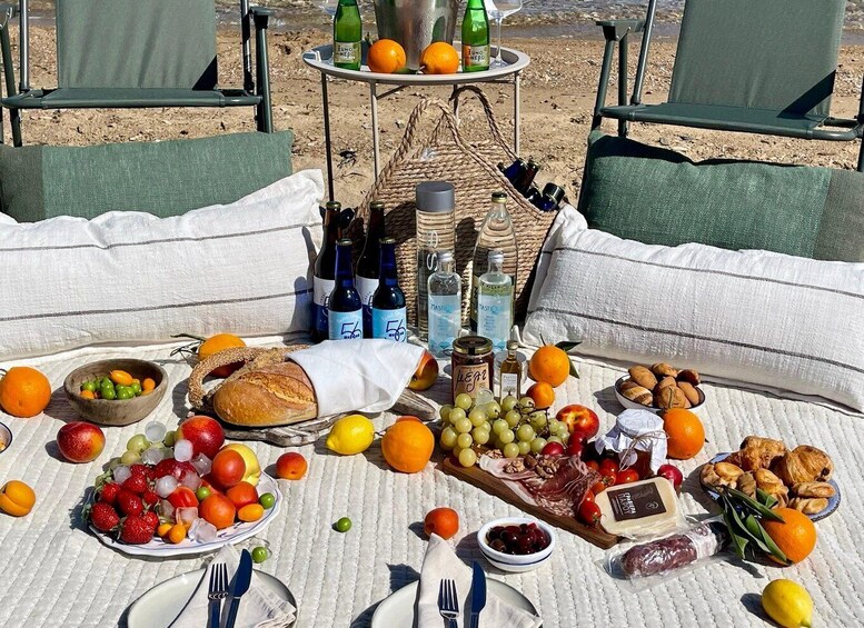 A picnic setup with food, drinks, and a bottle of wine on a beach. 2