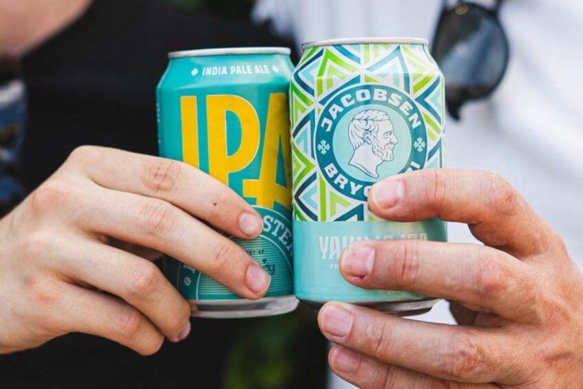 Two hands holding a can of India Pale Ale and a can of Jacobsen Bryg. 5