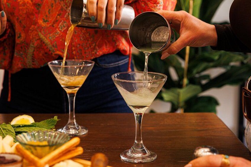 A person pouring a liquid into a martini glass. 2