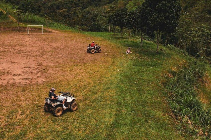 A dirt field with two ATVs and a child playing. 2