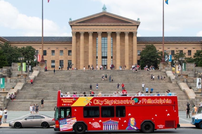 A red City Sightseeing bus in front of a large classical building with columns. 4