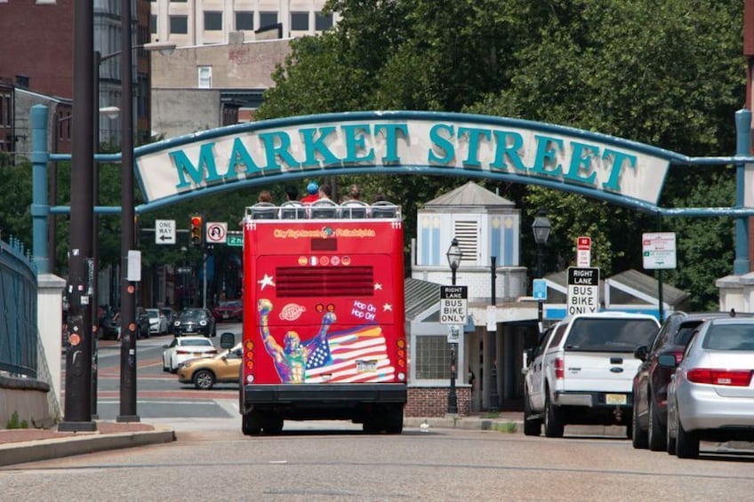 A bus with a colorful design on Market Street, surrounded by cars and traffic signs. 3