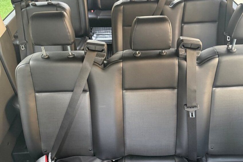 The interior of a vehicle with grey leather seats and seat belts. 5