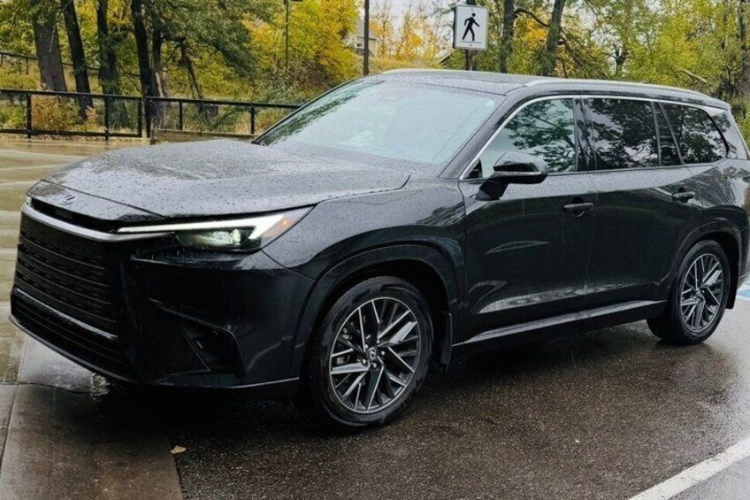 A black SUV parked on a wet road with trees in the background. 4