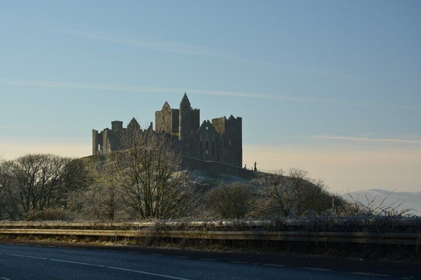 A historic castle on a hill with a road in the foreground. 4