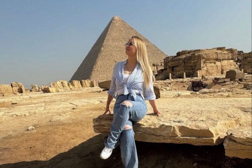 A person sitting on a rock with the Great Pyramid of Giza in the background. 5