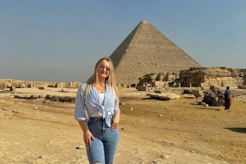 A person standing in front of the Great Pyramid of Giza with ancient ruins in the background. 2