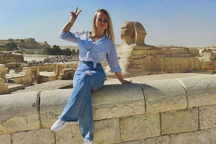 A person sitting on a stone wall with the Great Sphinx in the background. 4