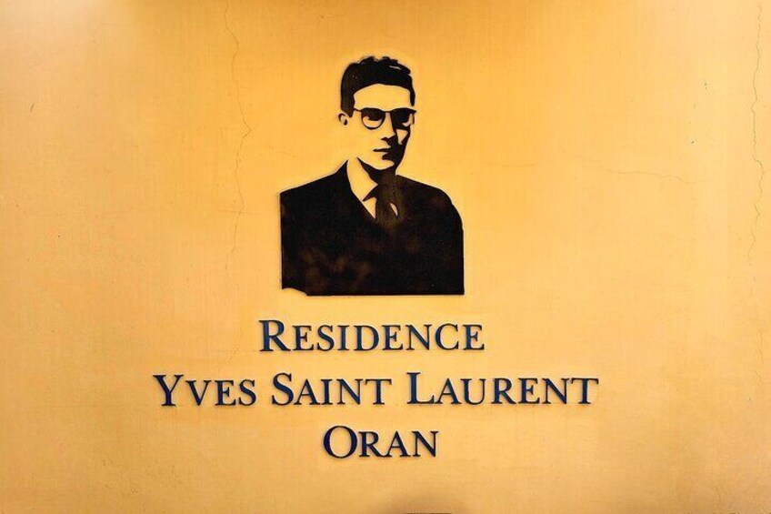 A wall with a portrait and text reading 'RESIDENCE Yves Saint Laurent Oran.' 2