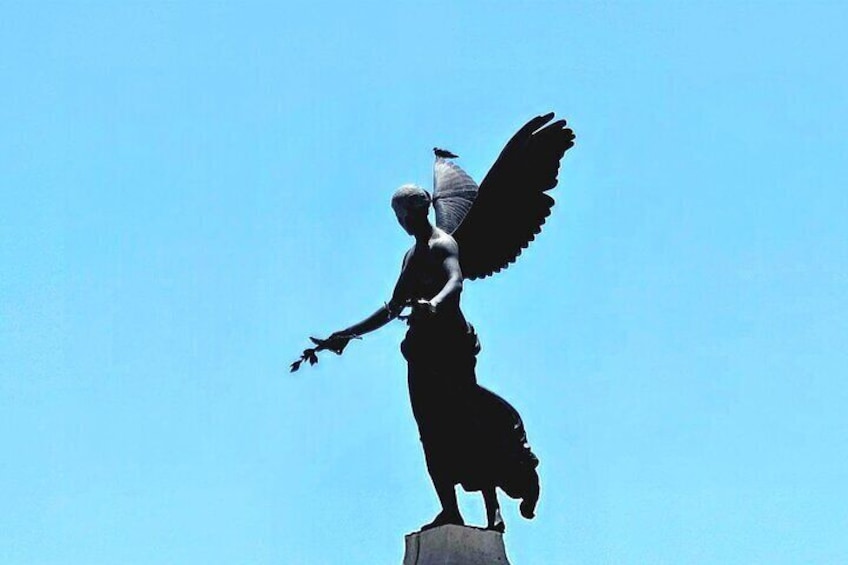 A statue of a winged figure with outstretched arms, standing on a pedestal against a clear sky. 5