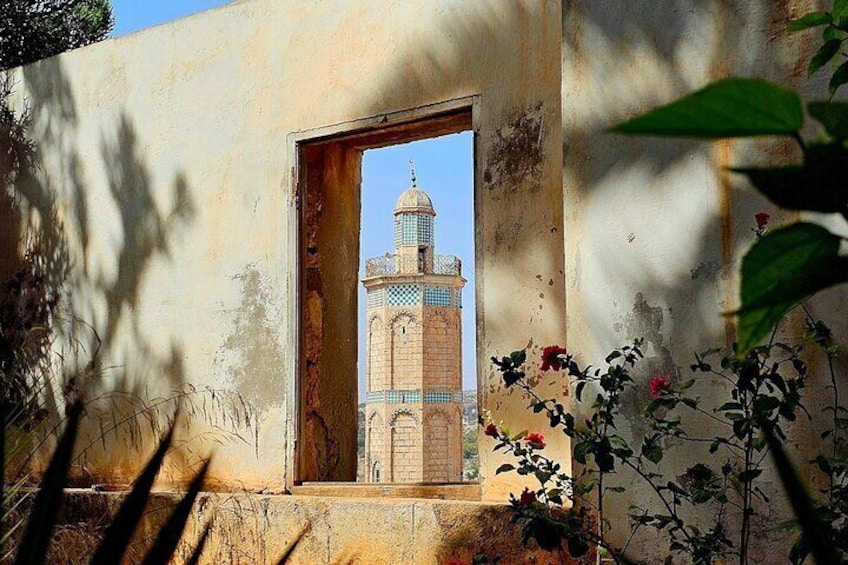 A weathered building with a doorway leading to a mosque with a blue dome. 1