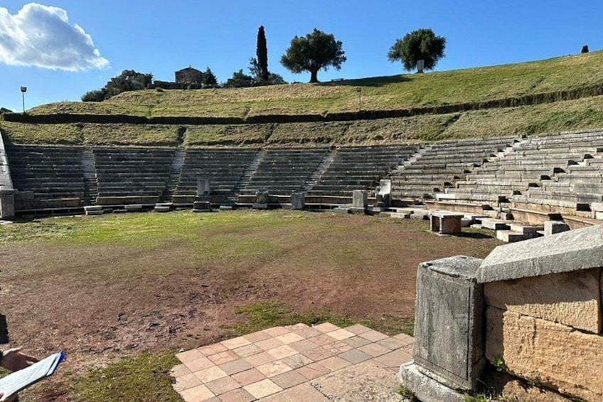 An ancient amphitheater with stone seating and a grassy hill in the background. 5