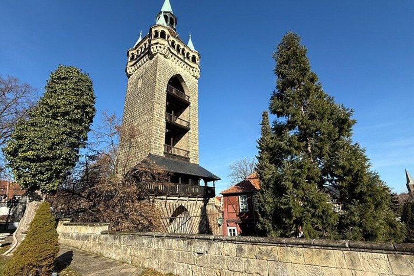 A stone tower with a balcony, surrounded by trees and a stone wall. 3
