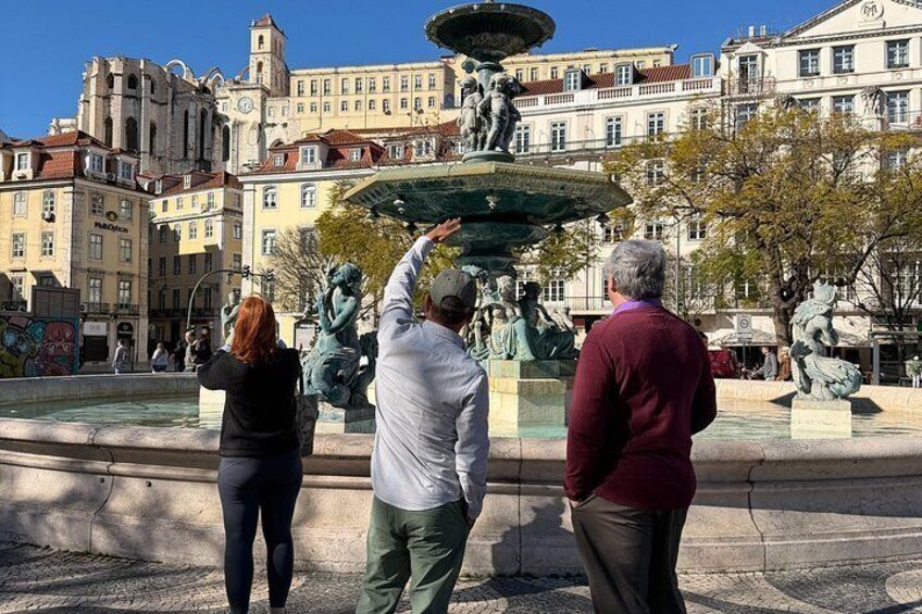 A fountain with statues, surrounded by buildings and trees. 2