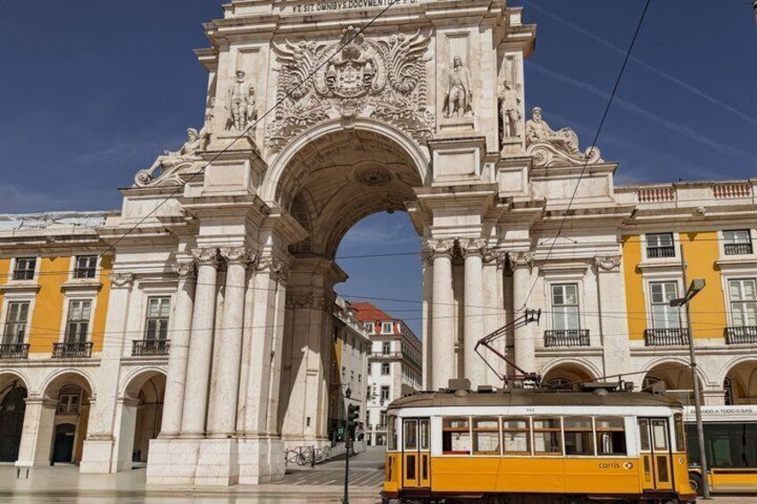 A historic archway with intricate carvings and a tram passing by. 4