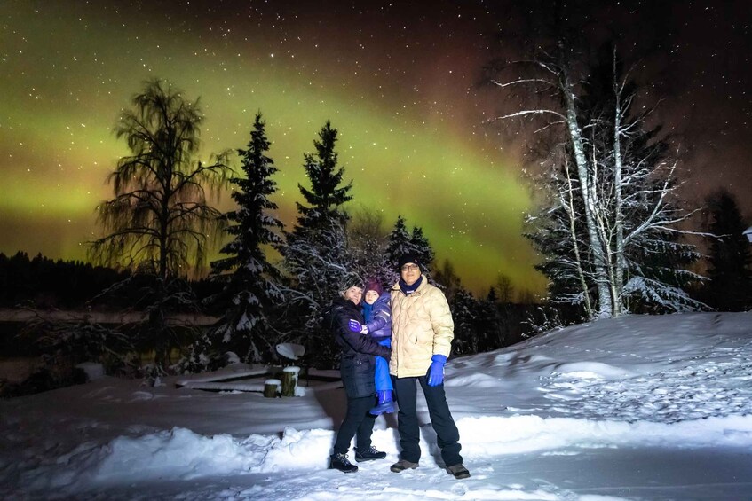 A family standing in snow with a northern lights display in the background. 4