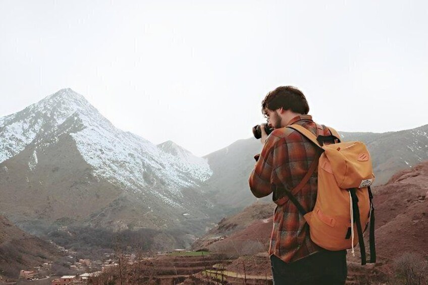 A person with a camera and a backpack in a mountainous landscape. 2