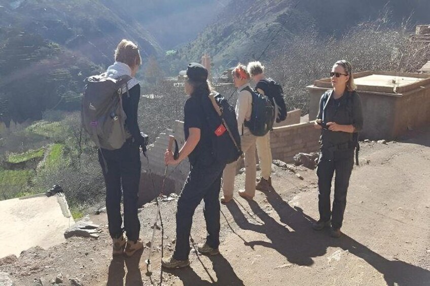 A group of hikers on a mountain trail with rocky terrain and a valley in the background. 5