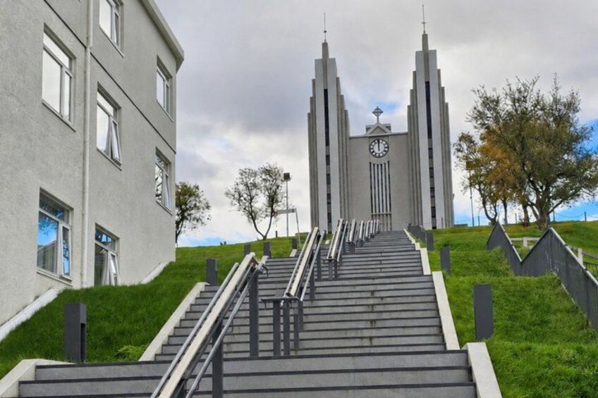 A modern building with a staircase leading to a clock tower. 1