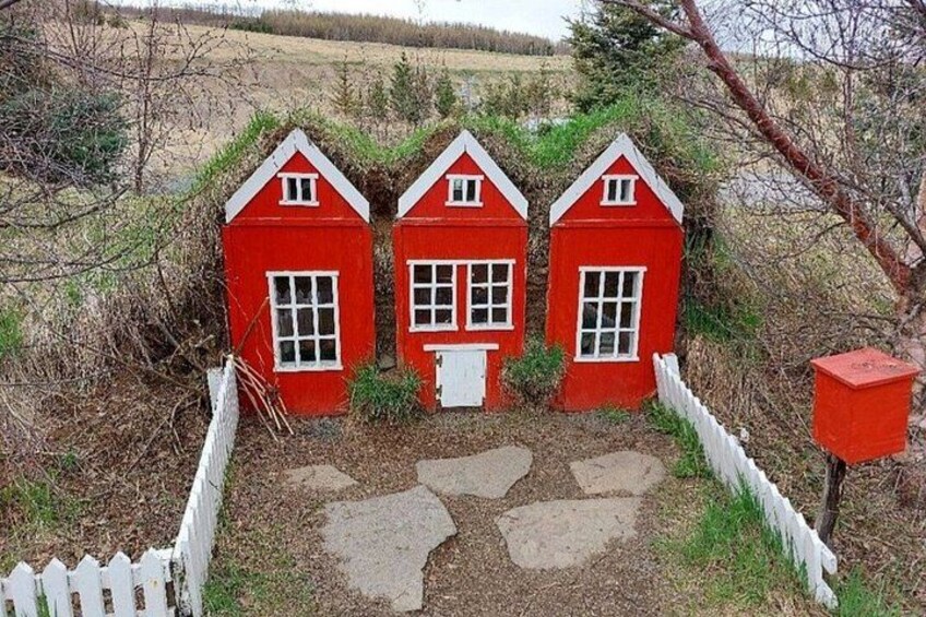 Three red houses with white trim, a white picket fence, and a stone pathway leading to them. 2