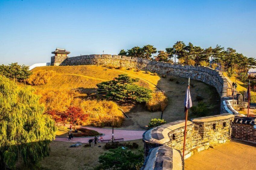 A stone fortification with a curved wall, a flagpole, and a clear sky. 2