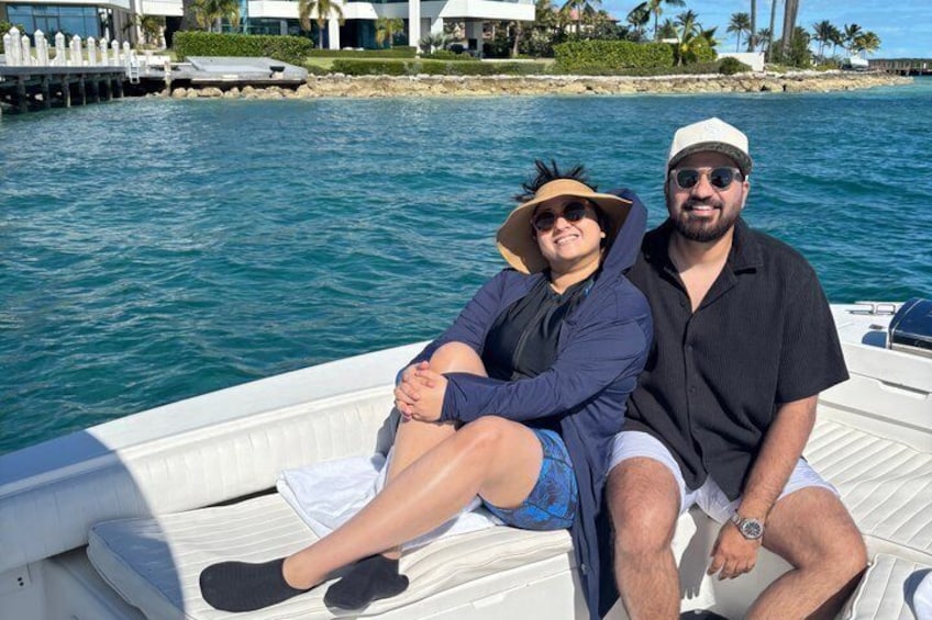 Two people on a boat with a beach and palm trees in the background. 2