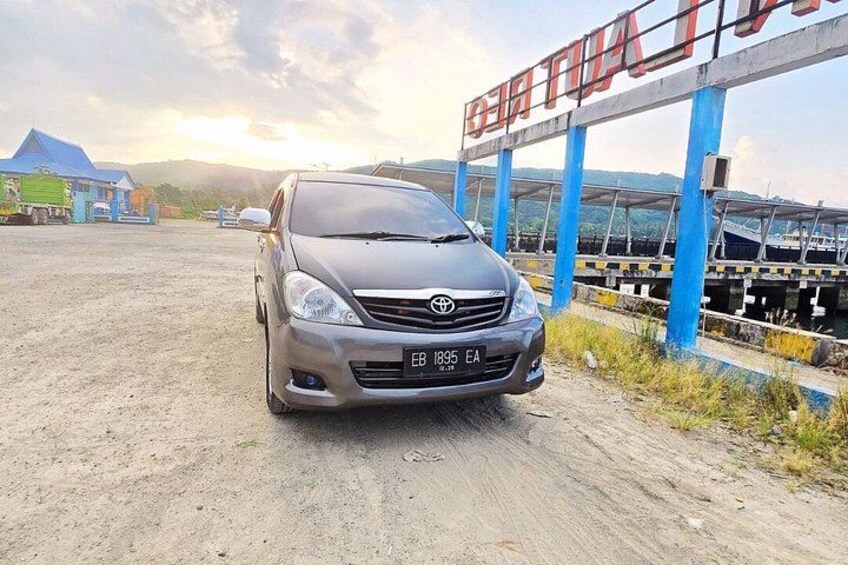 A Toyota car parked on a dirt road with a blue and white structure in the background. 2