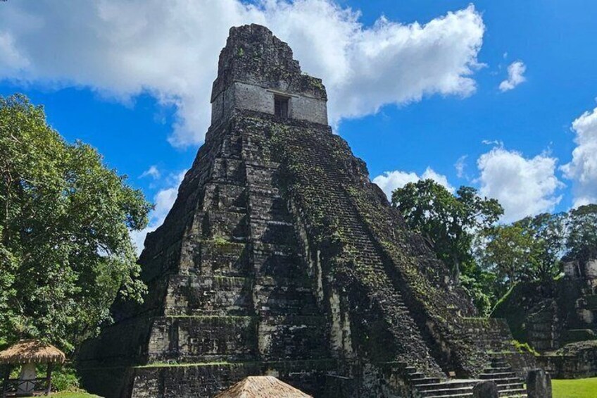 A large, ancient pyramid-like structure with a flat top, surrounded by lush greenery and trees. 1