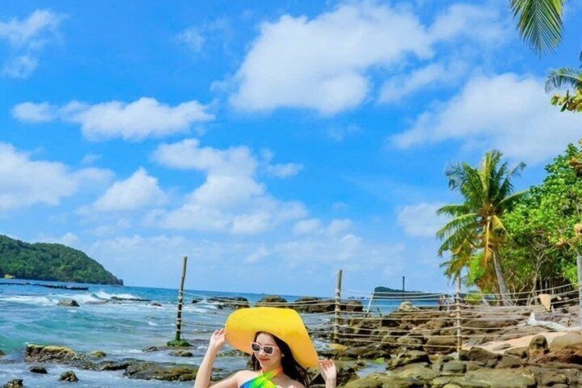 A beach with rocky shorelines, palm trees, and a clear blue sky. 2
