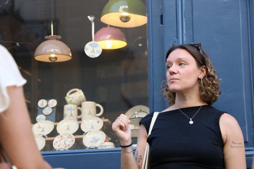 A person standing in front of a shop window displaying ceramic mugs and a clock. 2