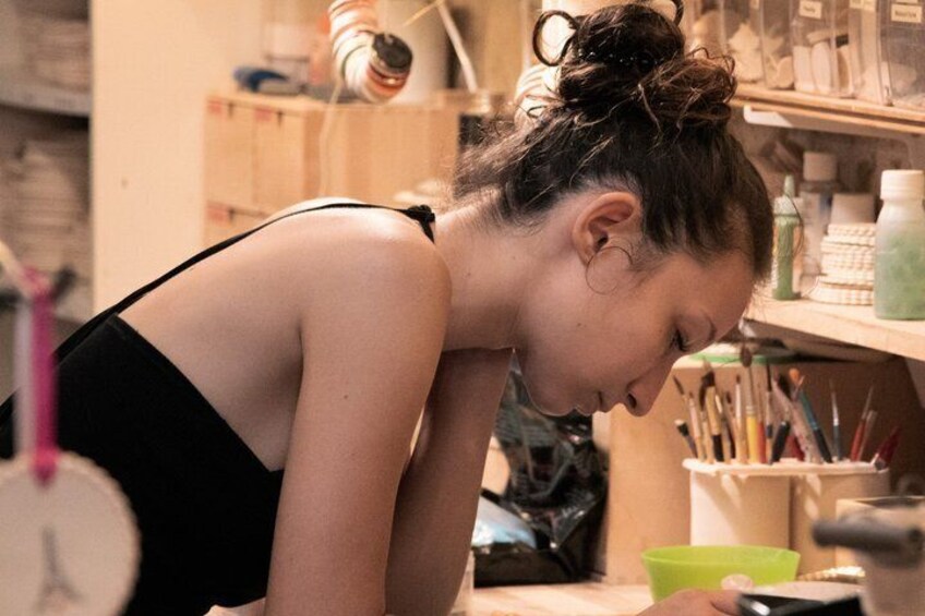A person in a black top working at a desk with art supplies. 5
