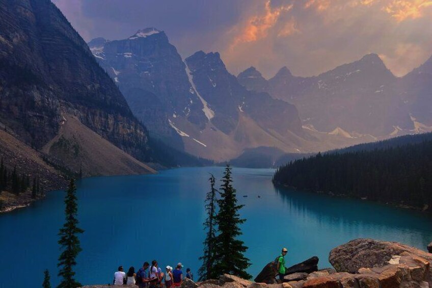 A group of people on a mountain overlooking a lake with mountains in the background. 5