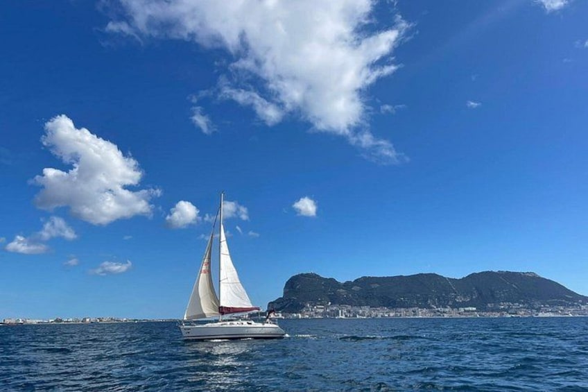 A sailboat on the water with a mountainous coastline in the background. 4