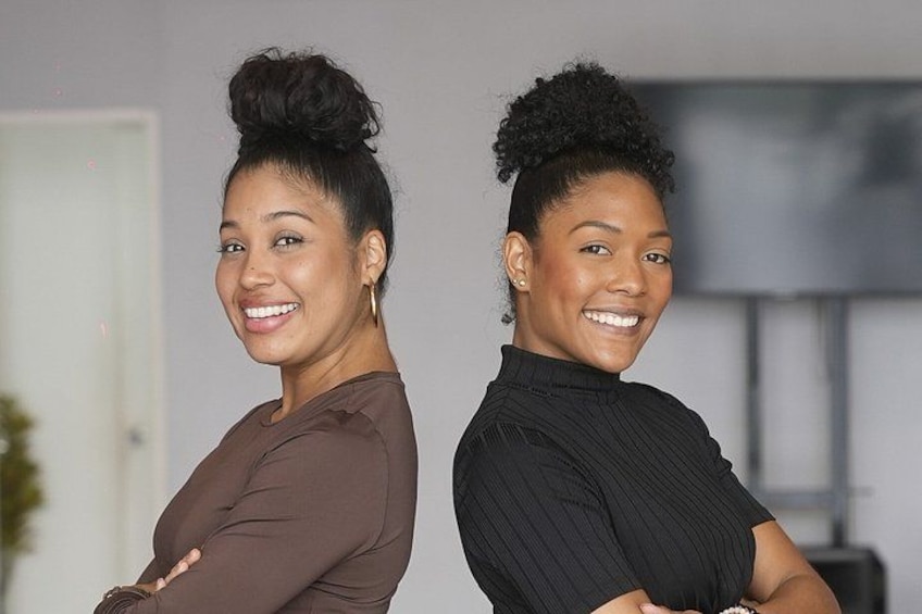Two individuals standing indoors with their arms crossed. 2